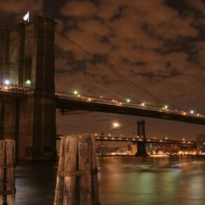 Brooklyn Bridge illuminated at night with the Manhattan skyline